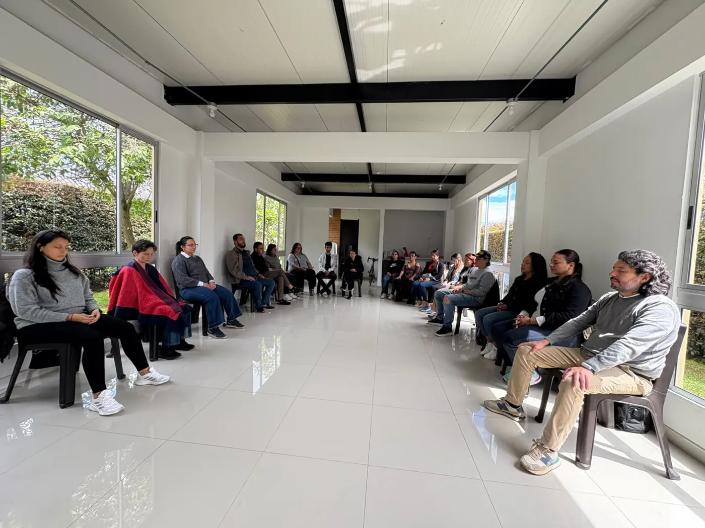 Personas sentadas en círculo durante un encuentro de constelaciones familiares guiado por Nikole Forero